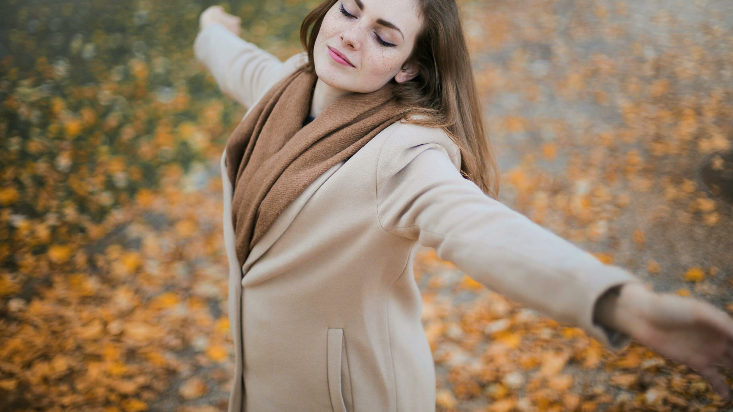 Woman in Beige Long Sleeve Coat Standing on Brown Leaves
