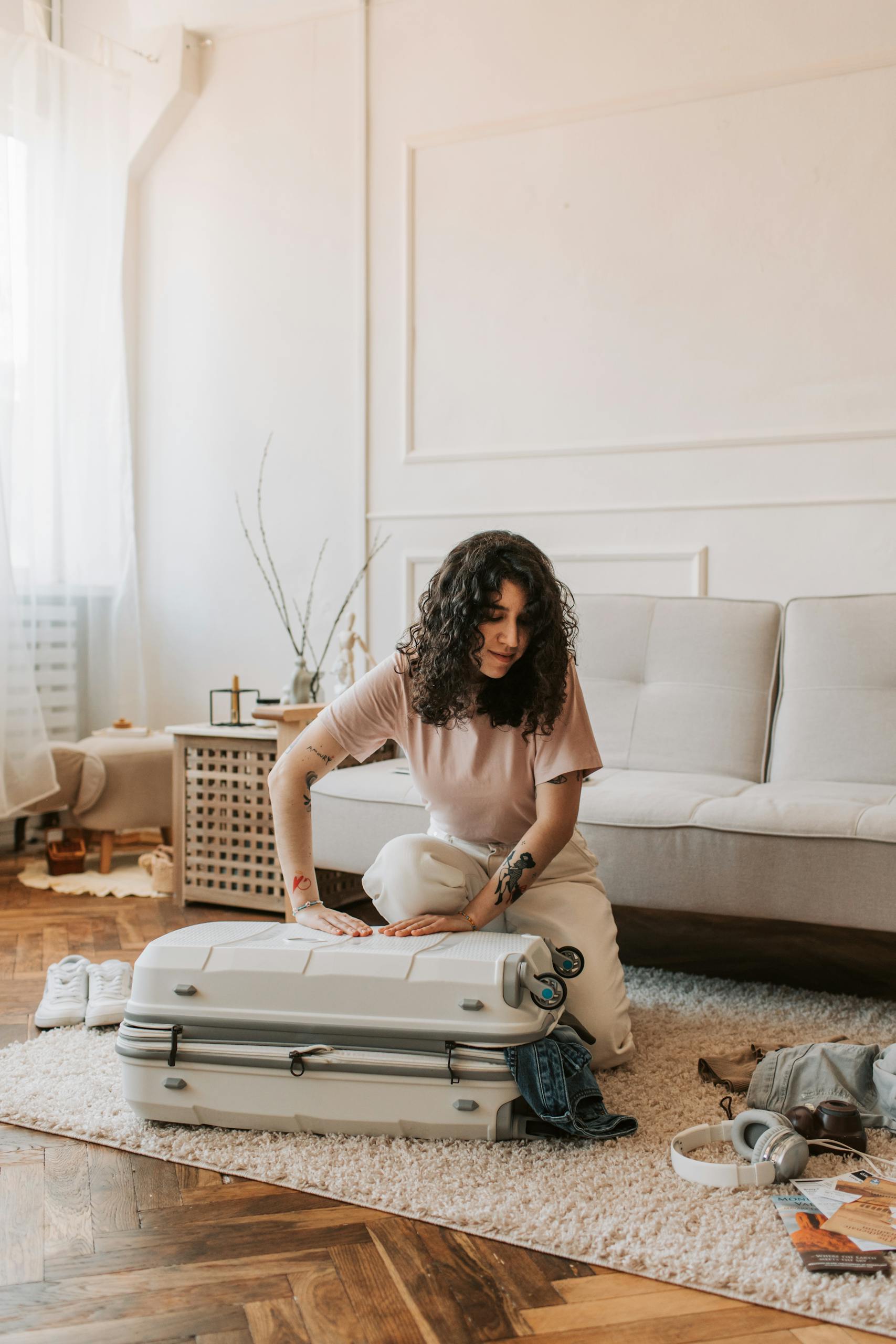 A woman is packing a suitcase in a cozy, sunlit living room, preparing for a trip.